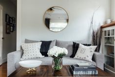 a living room with a couch, coffee table and mirror on the wall above it