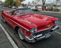 an old red car is parked on the side of the road