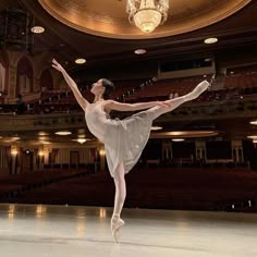 the ballerina is posing in front of an empty stage with chandelier and chandeliers