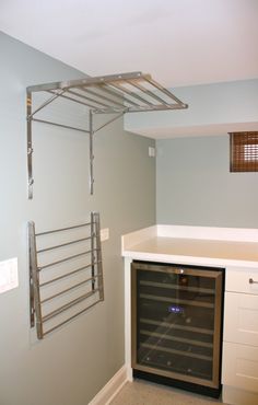 an empty wine cellar in the corner of a room with gray walls and white cabinets