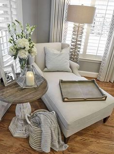 a living room filled with furniture and flowers on top of a wooden table next to a window