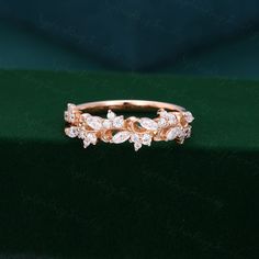 a gold ring with three diamonds on the top and bottom, sitting on a green velvet surface