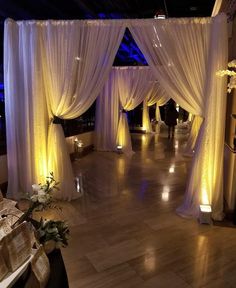 a room decorated with white drapes and candles for a wedding or special event in the evening