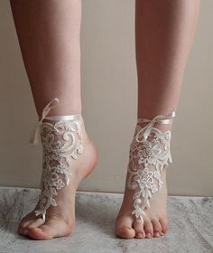 a woman's feet with white lace barefoot sandals on top of her toes and one foot in the air