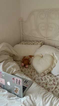 an open laptop computer sitting on top of a bed next to pillows and blankets with teddy bears