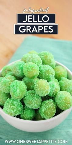 a white bowl filled with green jello grapes on top of a wooden table next to a blue napkin