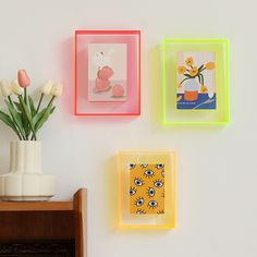 three square glass plates mounted to the side of a wall with flowers in vases