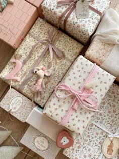 there are many wrapped presents on the floor together and tied with ribbons, including one for a baby's first birthday