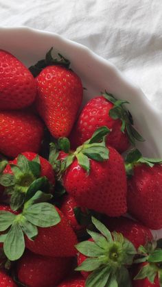 a white bowl filled with lots of ripe strawberries