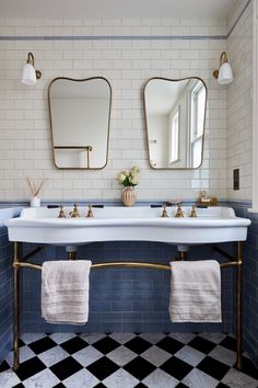 a bathroom with two sinks and mirrors on the wall next to towels hanging from a rack