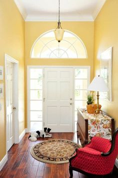 two cats are sitting on the hardwood floor in front of a white door with arched window