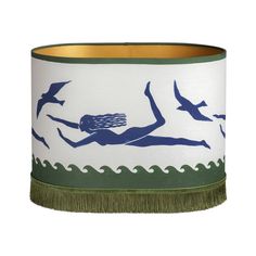 a blue and white lamp shade with a woman swimming on the water, birds flying around