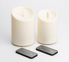 two white candles sitting next to each other with remote controls in front of the candle