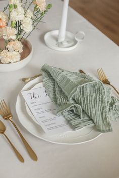 a place setting with napkins and flowers on the table