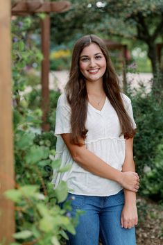 a young woman is posing for a photo in the garden with her hands on her hips