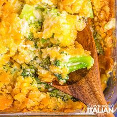 a casserole dish with broccoli, cheese and bread in it on a wooden spoon