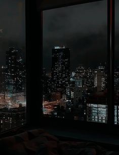 the city lights are lit up at night from an apartment window sill in this dark room