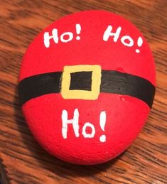 a painted rock with the words ho ho written on it and a santa hat sitting on top