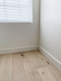 an empty room with white walls and wood flooring on the bottom half of it