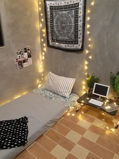 a room with a bed, laptop and lights on the wall above it is lit up by string lights