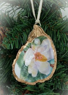 an ornament hanging from a christmas tree with flowers painted on the front and back