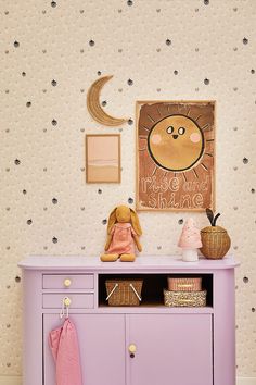 there is a purple dresser in the room with pictures on the wall and a teddy bear sitting on top