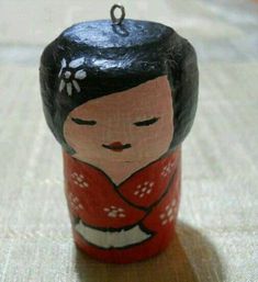 a small wooden doll with a red kimono on it's head and black hair