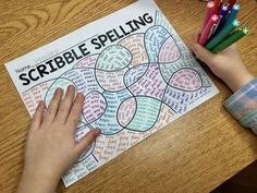 a child's hands holding colored crayons next to a printable scribble spelling game