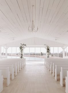 an empty church with white pews and chandelier hanging from it's ceiling