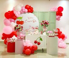 a table topped with lots of pink and red balloons next to a white counter top