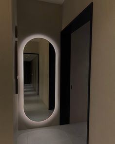 an empty hallway with a round mirror on the wall and lights in the doorways