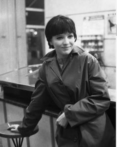 a black and white photo of a woman in a trench coat