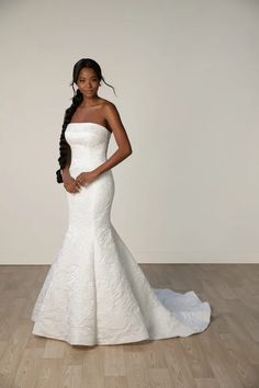 a woman in a white wedding dress standing on a wooden floor with her hands on her hips