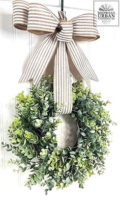 a wreath with a bow hanging from the front door, decorated with greenery and ribbon