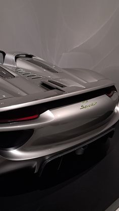 a silver sports car is on display in a showroom with white walls and black flooring