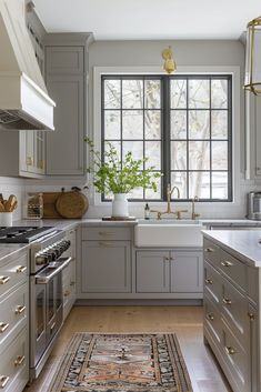 a kitchen with gray cabinets and white counter tops, an area rug on the floor