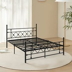 a black metal bed frame sitting on top of a white rug next to a window