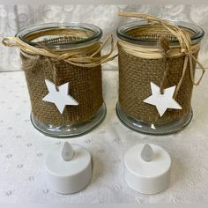 two mason jars with white stars on them sitting next to twine string and twine