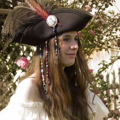 a woman wearing a black hat with feathers and beads