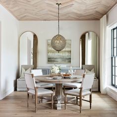 a dining room table with four chairs and a chandelier hanging from the ceiling