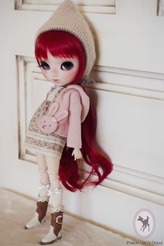 a doll with long red hair is standing next to a white door and wearing a hat