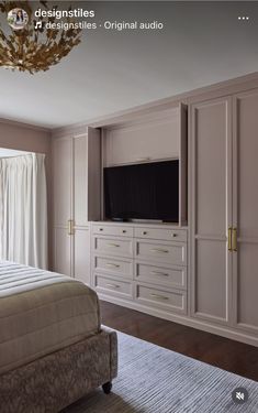 a bedroom with a bed, dressers and television on the wall in front of it