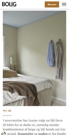 a bed sitting next to a window with a coat rack on the wall above it