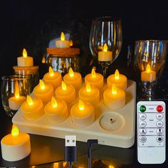 many lit candles on a tray with remote controls