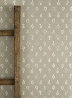 an old wooden ladder stands in front of a wallpapered background