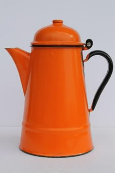 an orange tea pot with a black handle