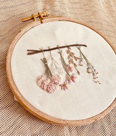 a close up of a embroidery on a piece of cloth with flowers and branches in it