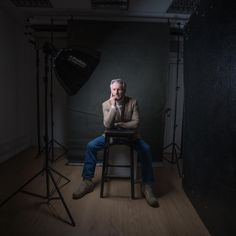 a man sitting in a chair with his hand on his face while posing for a photo