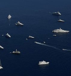 a group of boats floating in the ocean next to each other near some smaller ships