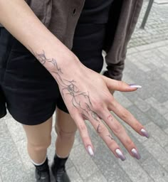 a woman's hand with a small tattoo on her left wrist and the other arm